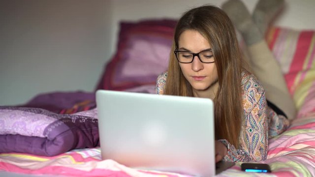 junge Frau arbeitet am Laptop auf dem Bett zu hause