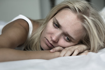Sad woman lying in bed depressed.