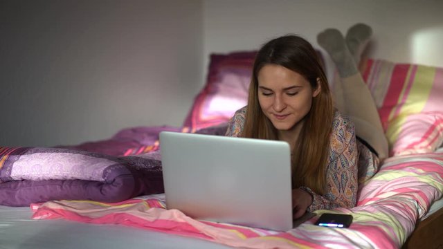 junge Frau hat Spa&szlig; am Laptop auf dem Bett zuhause