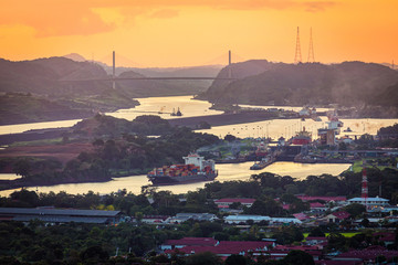 Container ships passing through Panama canal in scenic landscape at sunset