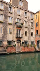 Old ivy covered building in Venice with reflection in water