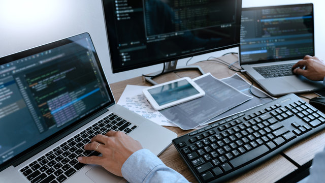 Programmer working On Computer In IT Office Typing Data Coding in software and checking code on computer screen.
