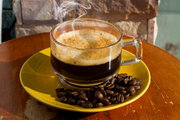 Clear coffee cups and beans on a wooden table in the morning natural light
