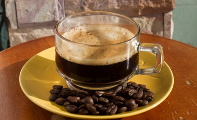 Clear coffee cups and beans on a wooden table in the morning natural light