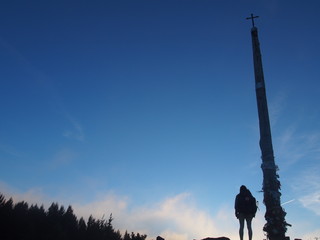 Pilgrim and beautiful blue sky with Cruz de Ferro (Cross of Iron) in the early morning, Camino de Santiago, Way of St. James, Foncebadon to Ponferrada, French way, Spain