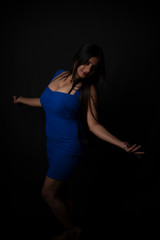 Fashion portrait of an young and attractive Indian Bengali brunette girl with blue western dress in front of a black studio background. Indian fashion portrait and lifestyle.