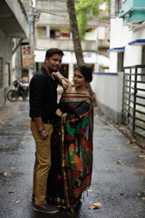 A brunette Indian Bengali romantic couple in traditional wear interacting between themselves in the...