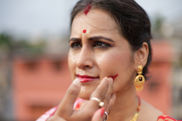 Portrait of beautiful smiling brunette Indian Bengali woman in traditional red sari having...