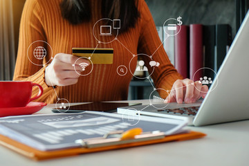 Female businessman use credit card to shopping online in internet website shop with computer laptop on work table in office.