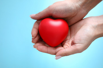 Woman hand hold red toy heart in hand closeup