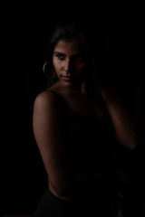 Fashion portrait of an Indian brunette Bengali dark skinned woman with black lingerie standing in black studio copy space background. Indian fashion photography and lifestyle.
