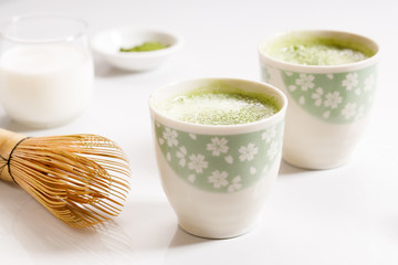 Hot green tea latte on white marble background