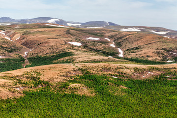 Mountain peaks covered with snowfields. Northern landscape. View from helicopter flight altitude
