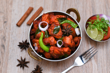 Fried chicken Kebab or Kabab, Chicken Tikka Masala in copper Kadai on wooden background Bangalore Hyderabad South India. Top view of Indian non veg food. 
