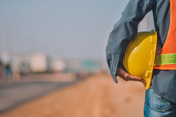 Close up Engineering holding Yellow helmet hard hat safety and Road construction background