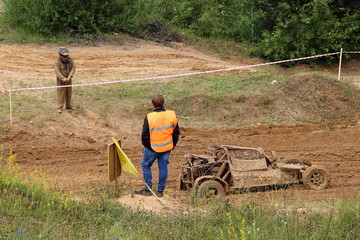 Muddy broken buggy car on off road track, dirty driver and referee on autocross racing
