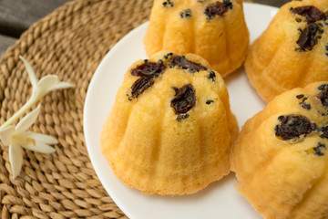 Close up of egg cake with raisin in white plate on wicker.