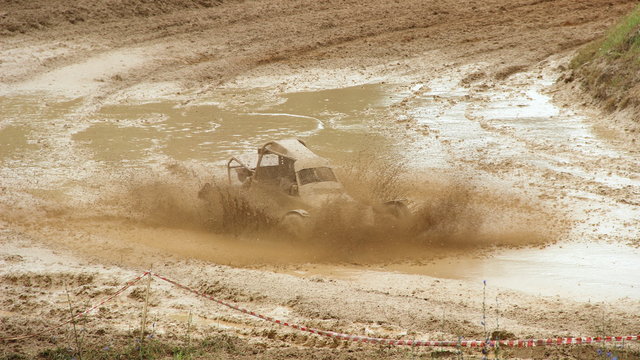 Fast Buggy car in muddy puddle dirt splash on off road track turn, front wide view