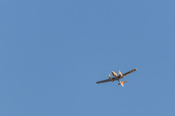 a twin-engined small airplane flies in the blue cloudless sky