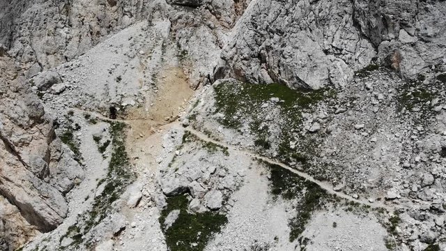 Wanderer mit Rucksack l&auml;uft motiviert einen engen, steinigen, steilen Wanderweg entlang in 4k