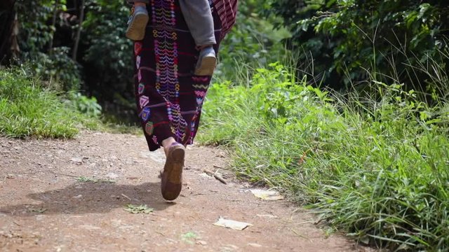 The Feet of a Guatemalan Woman Carrying her baby walking home in traditional woven skirt