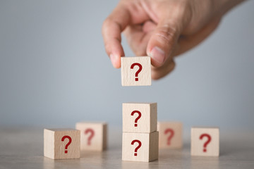 Hand arranging wood block stacking with icon question mark,thinking with question mark concept.