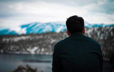 fashionable man sits on edge overlooking beautiful lake