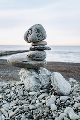 The figure of stones standing on each other, on the beach against the sea.