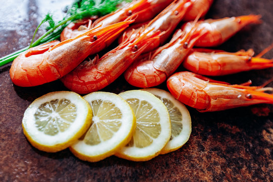 Fresh shrimp with lemon and dill on the red table. © EwaStudio