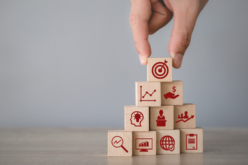 Hand arranging wood block stacking with icon arrow and business,targeting the business concept.