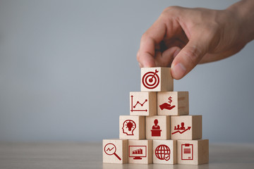 Hand arranging wood block stacking with icon arrow and business,targeting the business concept.