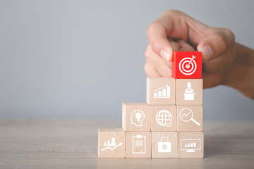 Hand arranging wood block stacking with icon arrow and business,targeting the business concept.