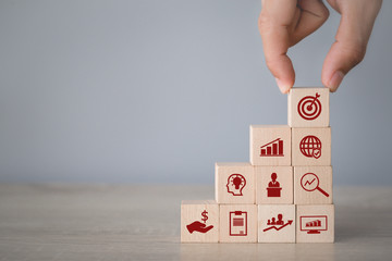 Hand arranging wood block stacking with icon arrow and business,targeting the business concept.