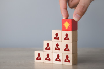 Hand choosing wood cube with icon light bulb and human symbol,creative idea and innovation concept.