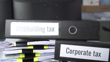 Stack of taxes binders report concept: Document of Withholding tax and corporate tax for accountant. withholding tax sometimes applies to royalties, rent or even sale duty must be paid to government