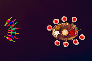 Til Gul OR Sweet Sesame Laddu with Miniature Fikri and Kite model with haldi Kumkum and sugar crystals for Makar Sankranti festival over moody background, selective focus