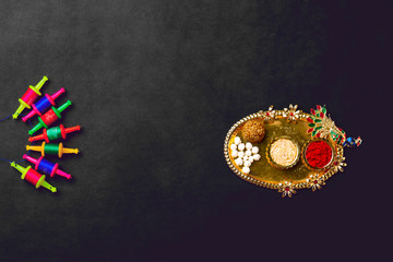 Til Gul OR Sweet Sesame Laddu with Miniature Fikri and Kite model with haldi Kumkum and sugar crystals for Makar Sankranti festival over moody background, selective focus