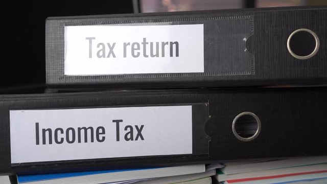 Tax return and Income tax files binder of report, document in office. completion of documentation that calculates entity&rsquo;s income earned  of payable to government, organisations or potential taxpayers