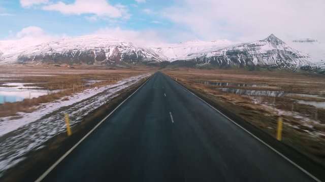 Aerial of a long road with mountains in the background during the winter in Iceland