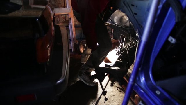 Mechanic removing the sub frame from underneath a salvaged motor vehicle