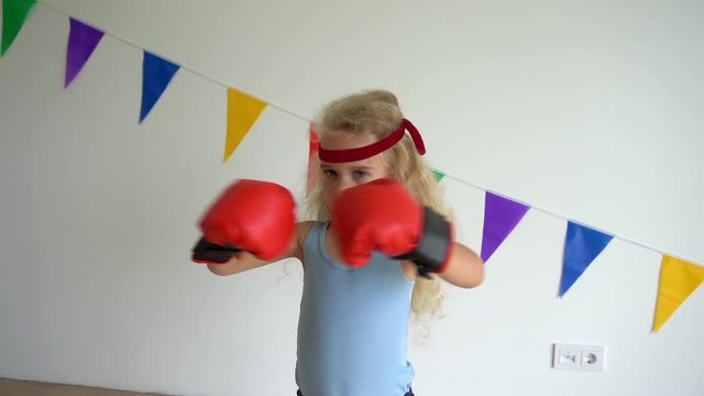 Child in boxing gloves. Aggressive little girl in boxing gloves. Slow motion