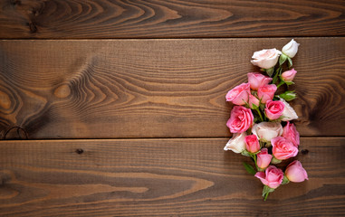 Floral composition with a wreath of pink roses on wooden background. Valentine's Day background. Flat lay, top view.