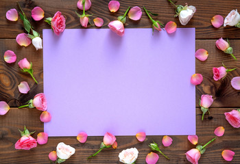 Valentine's Day background. Round frame floral pattern  made of pink and beige roses, green leaves on wooden background. Flat lay, top view.