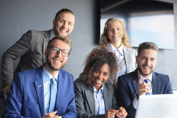 Fototapeta premium Happy business people laugh near laptop in the office. Successful team coworkers joke and have fun together at work.