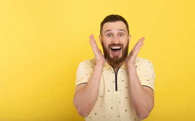 Portrait of young surprised man with opened mouth on yellow.