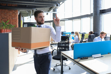 Dismissed worker going from the office with his office supplies showing fuck