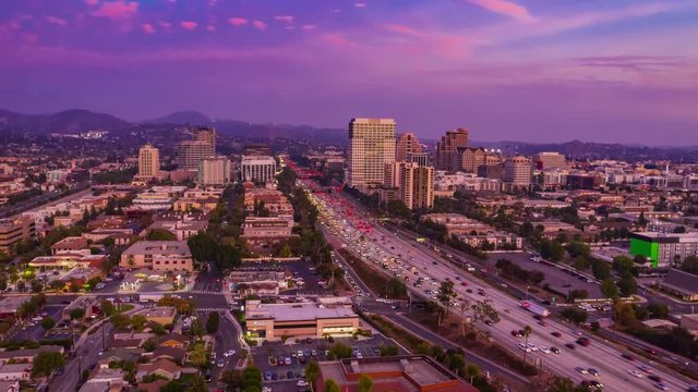Aerial time lapse in motion of a beautiful  sunset over Los Angeles city in California with freeway and cars below.