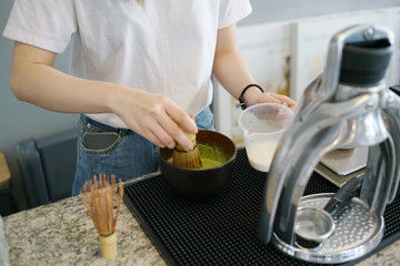 Girl making matcha latte, green tea with milk, traditional matcha tools, bamboo whisk