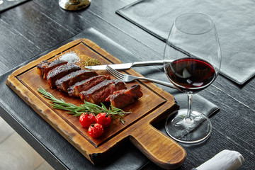 fried boiled pork, cut into slices, lying on a wooden board, decorated with tomatoes, tarragon, herbs