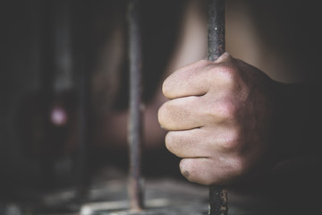 Man in prison hands of behind hold Steel cage jail bars,  Male prisoners were severely strained in...